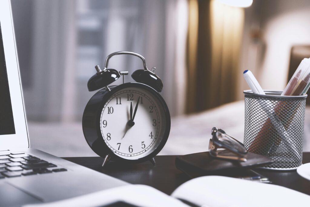 pexels-photo-714701-714701 A classic analog alarm clock on a modern desk setup with a laptop and pens, creating a balanced workspace vibe.